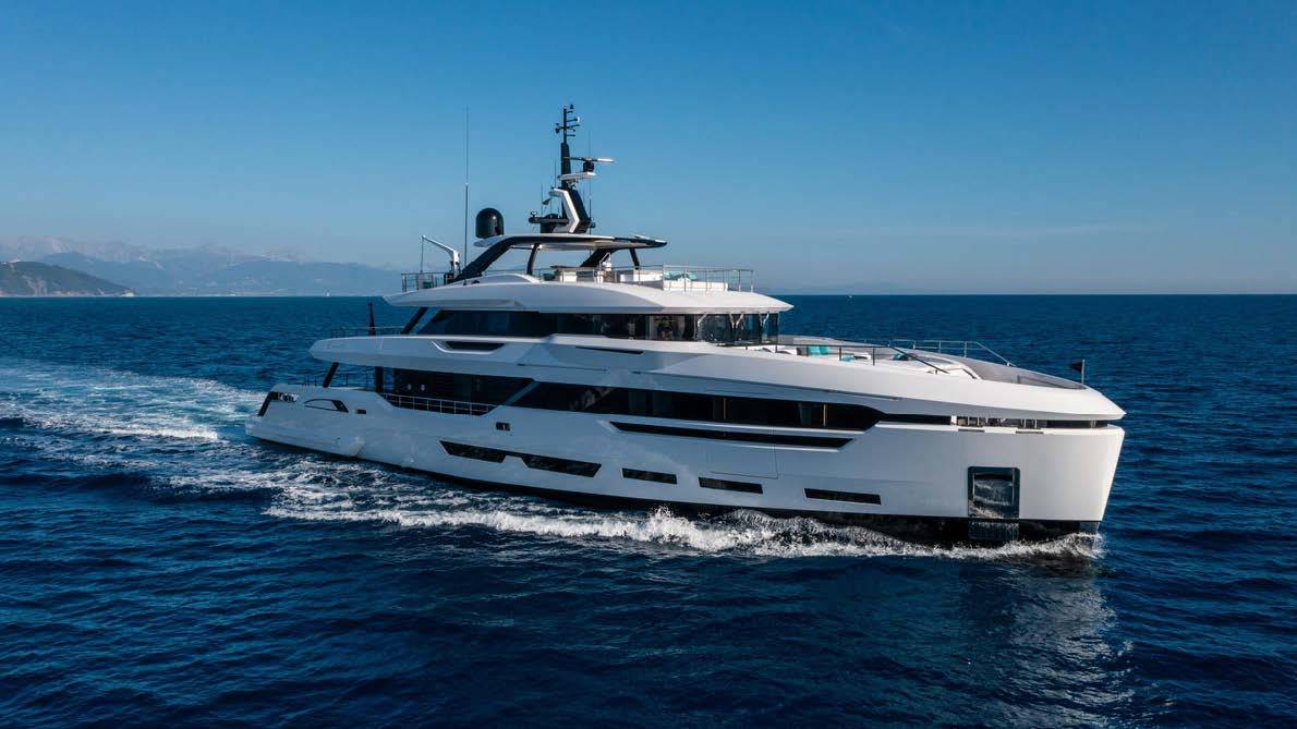 A sleek white superyacht glides through deep blue waters under a clear sky.