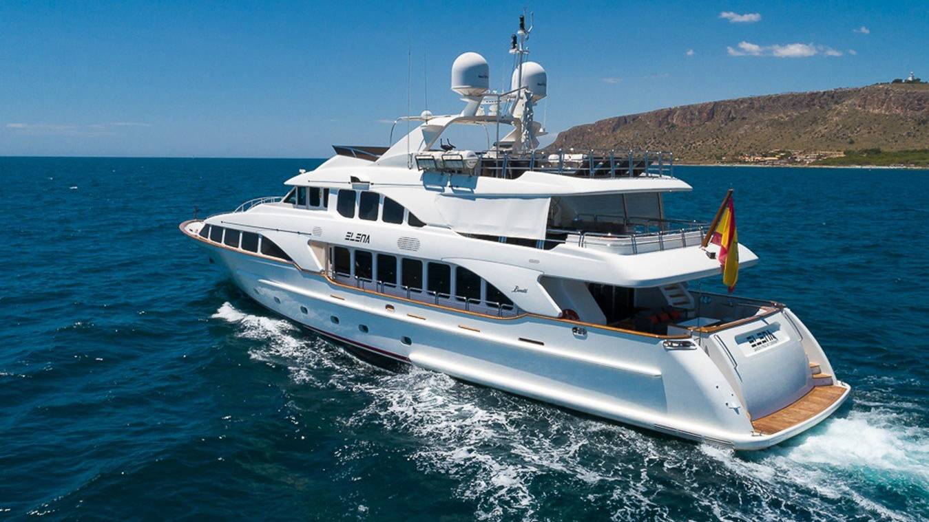 A luxurious white yacht cruises through the deep blue ocean under a clear sky.