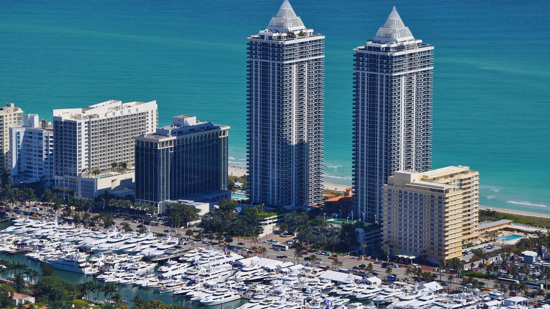 Luxury yachts fill the harbor in front of Miami's iconic skyscrapers and the turquoise ocean.