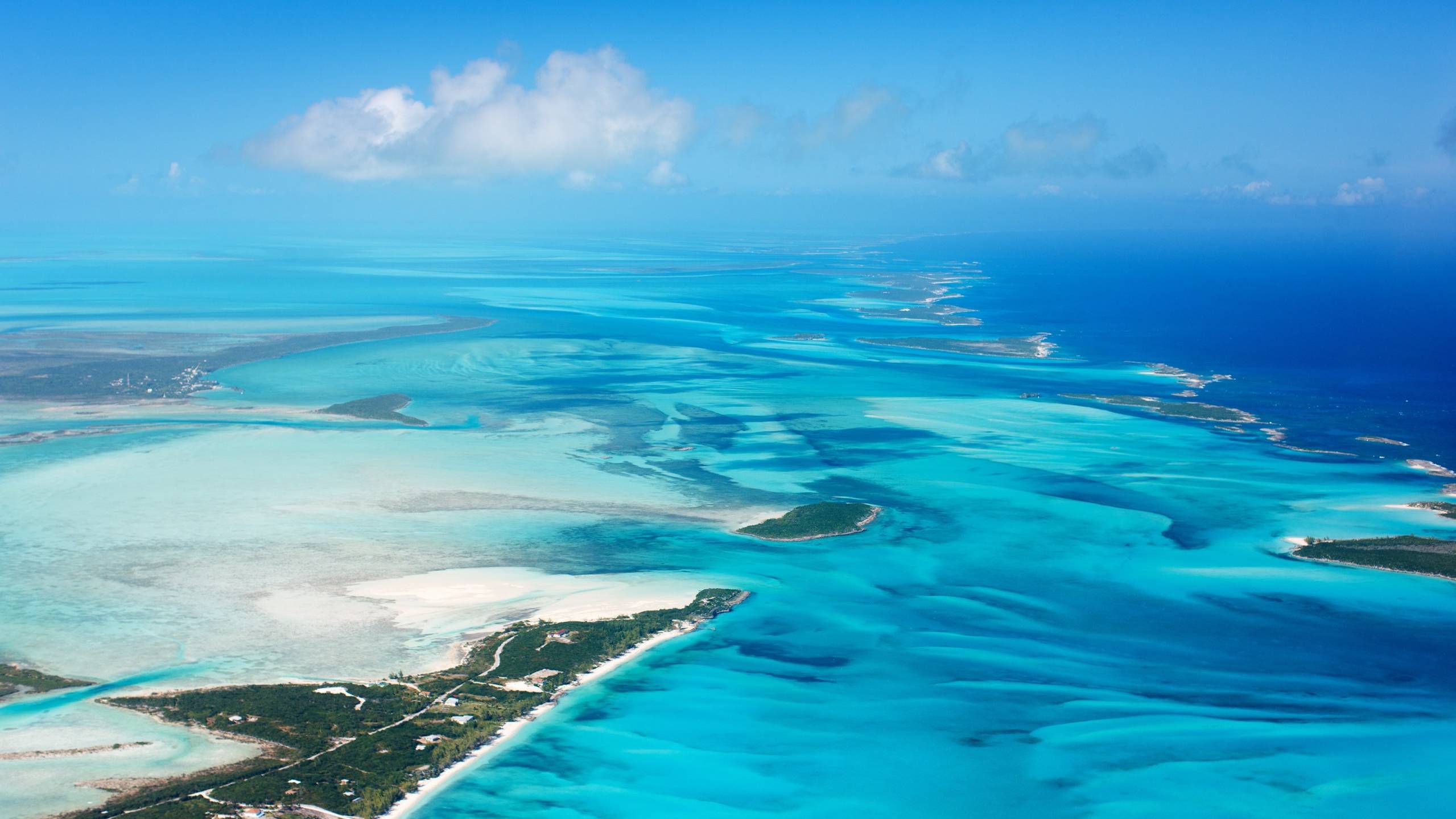 Expansive turquoise waters and scattered islands create a breathtaking aerial view of a tropical paradise.