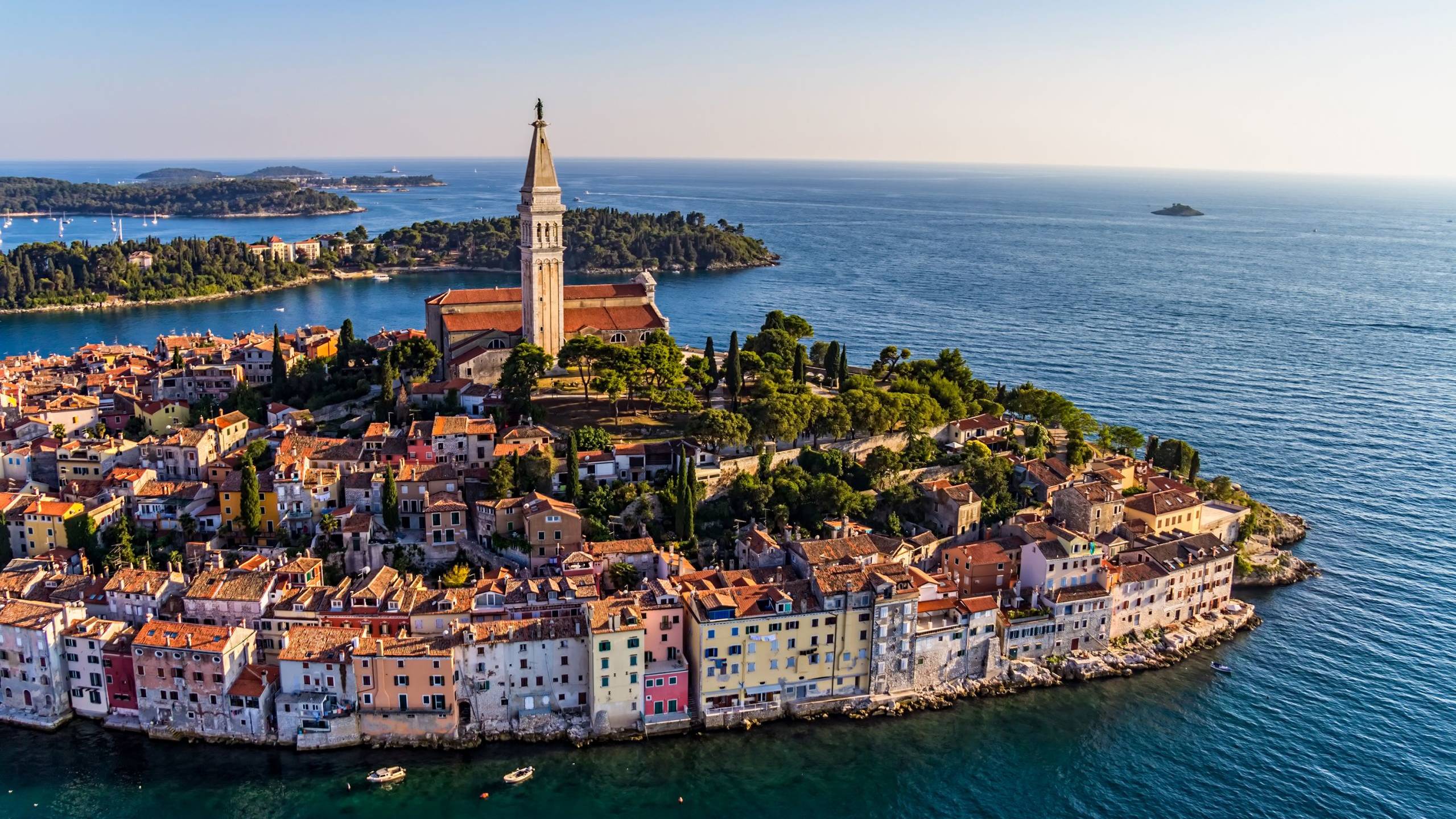 The charming coastal town of Rovinj, Croatia, is bathed in the warm glow of the setting sun, its colorful buildings cascading down to the azure Adriatic Sea.