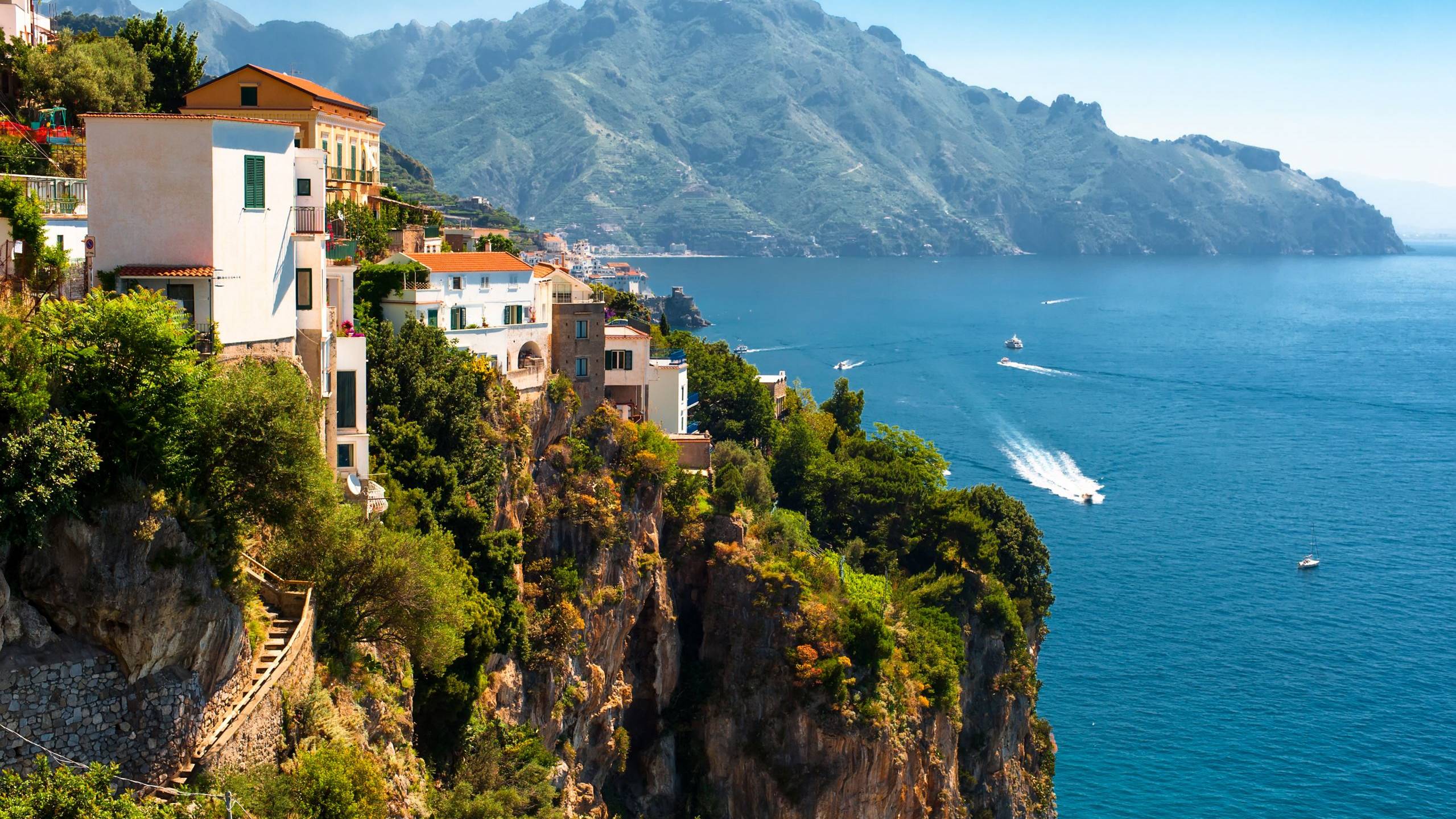 Charming white villas cling to a dramatic cliffside overlooking the sparkling azure waters of the Amalfi Coast.