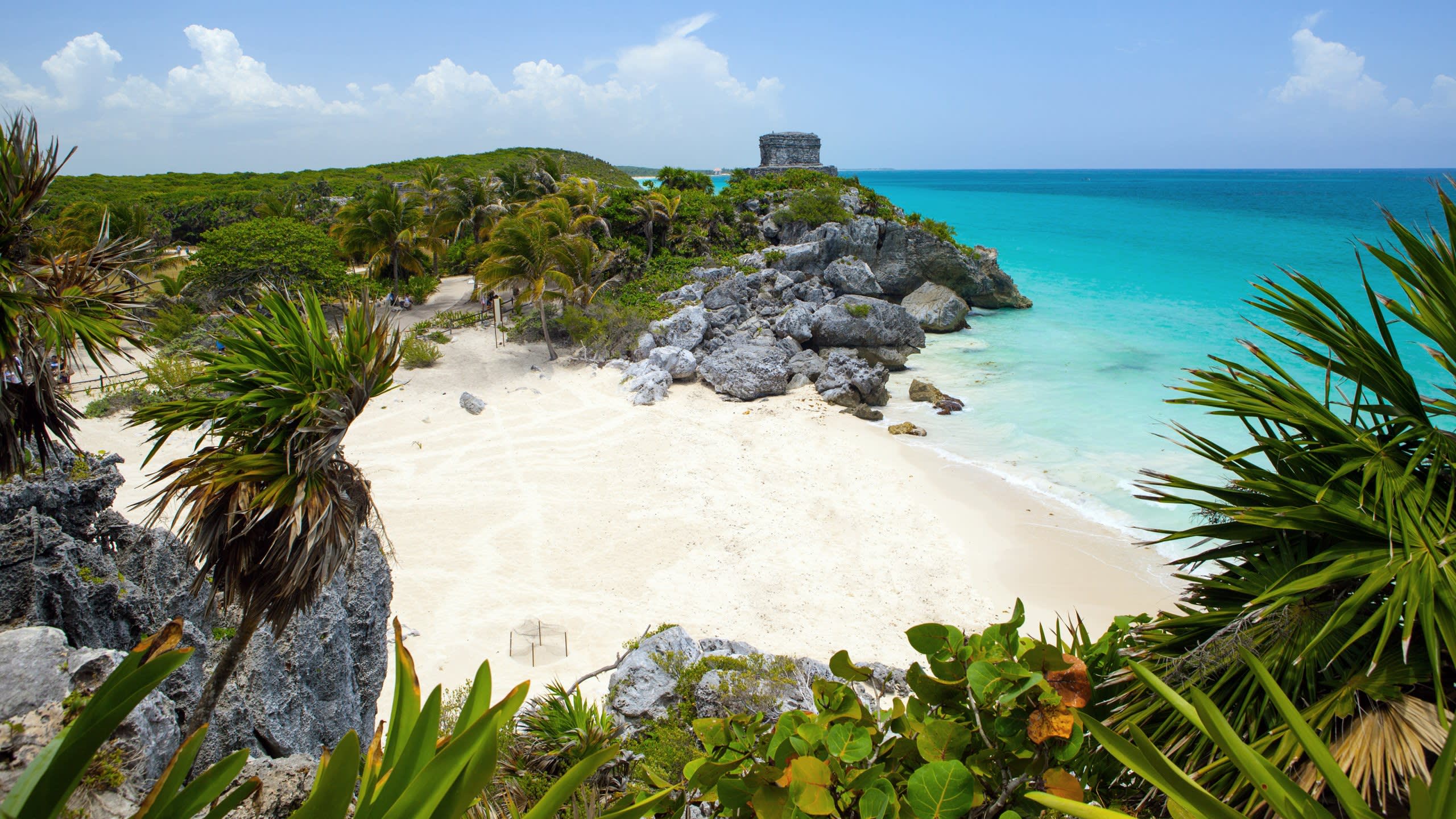 Ancient Mayan ruins stand majestically above the turquoise waters of the Caribbean Sea.
