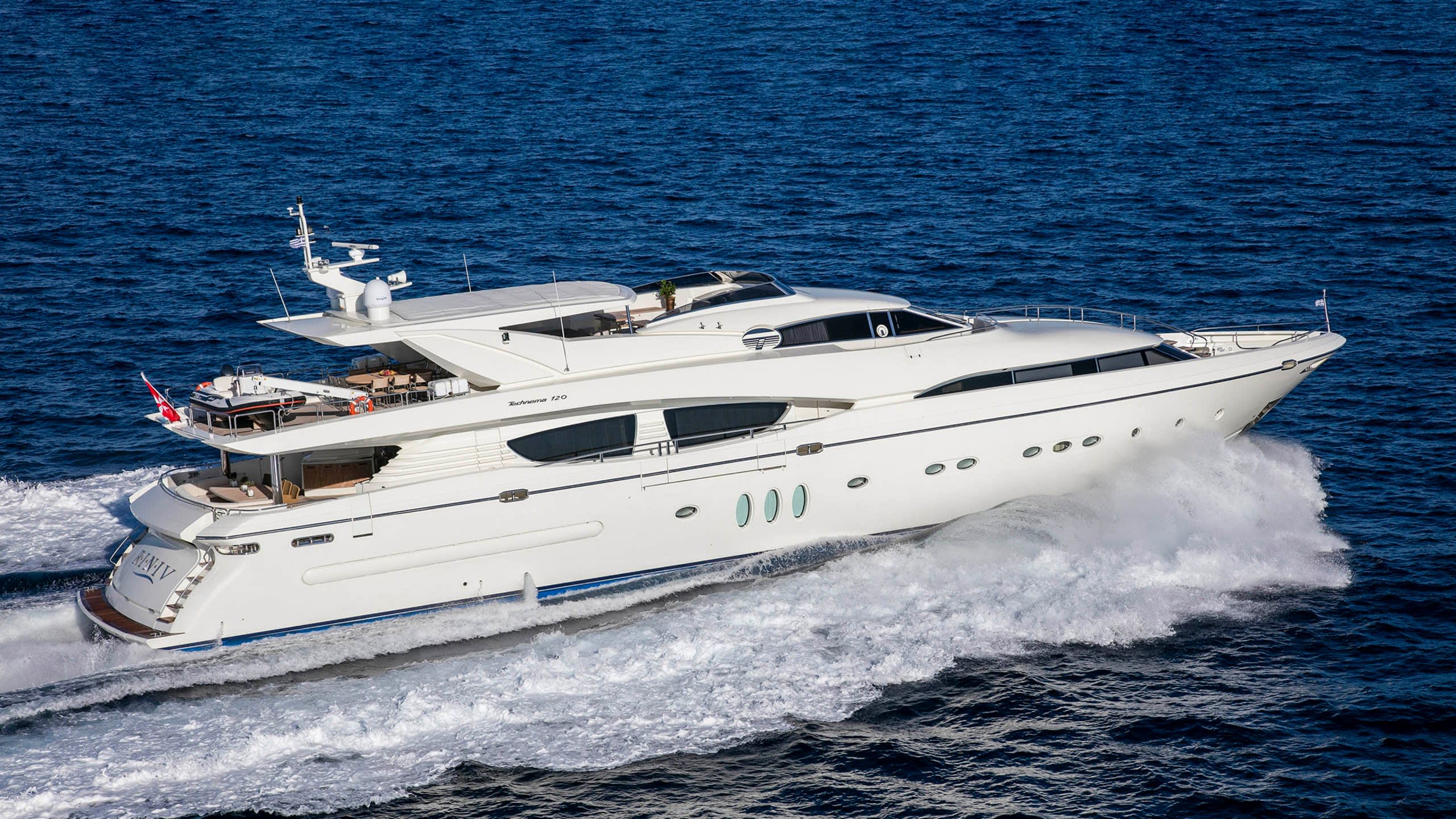 A sleek white yacht cuts through the deep blue ocean, leaving a trail of white spray in its wake.