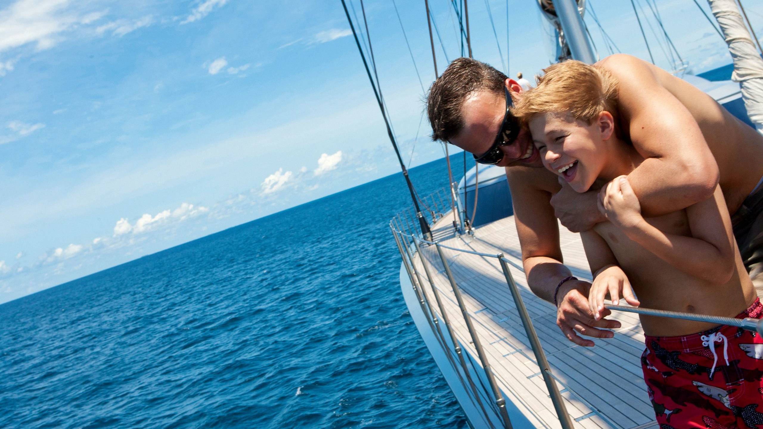 Father and son smile looking out onto the ocean