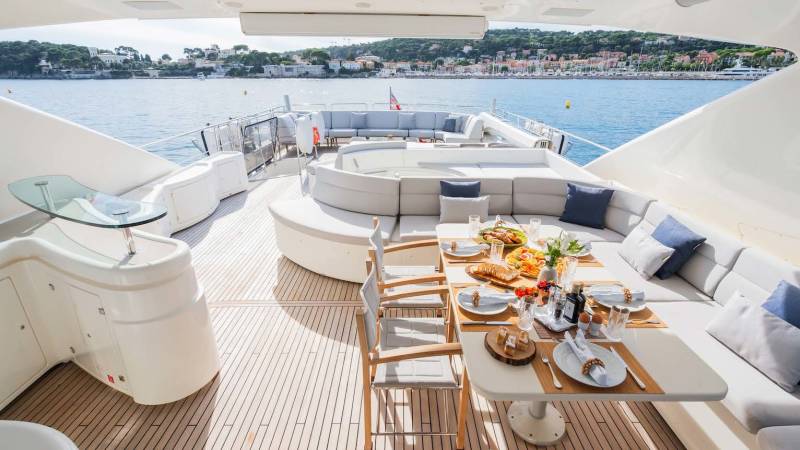 A beautifully set table awaits on the deck of a luxury yacht, overlooking a picturesque coastal town.