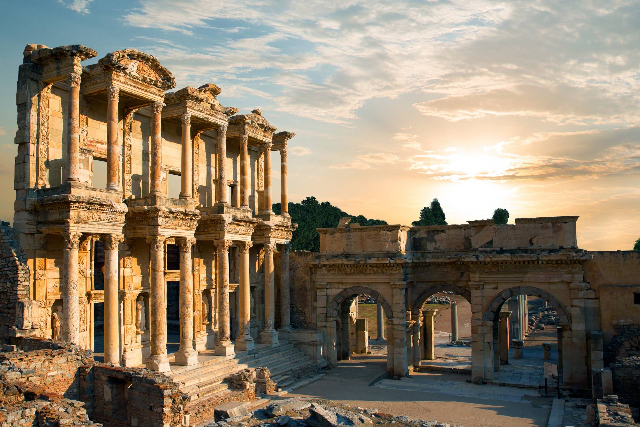 Ancient Roman ruins bask in the warm glow of a sunset, with intricate columns and arches standing testament to a bygone era.