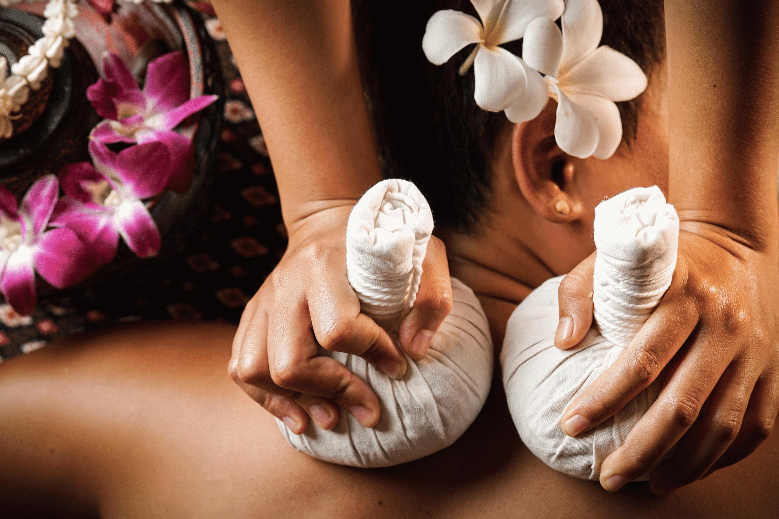 Experience ultimate relaxation with a traditional Thai herbal compress massage, adorned with fragrant plumeria flowers.