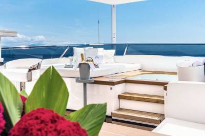 Luxurious yacht deck features a hot tub, plush seating, and a chilled champagne bucket ready for enjoyment.