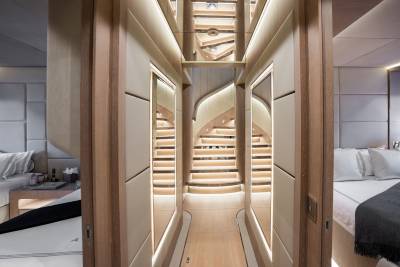 Luxurious yacht interiors feature a stunning mirrored staircase and elegantly appointed bedrooms.