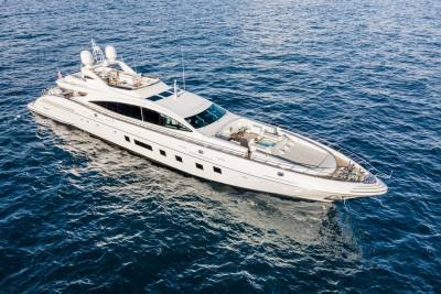 A luxurious white yacht glides through the deep blue ocean under a bright sky.