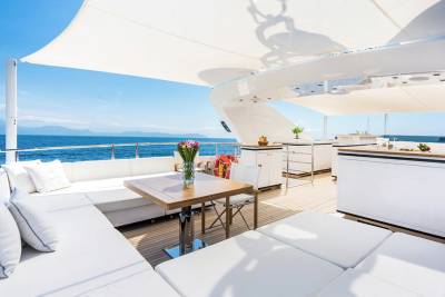 Relax on the luxurious deck of this yacht, complete with comfortable seating and a dining area overlooking the sparkling blue ocean.