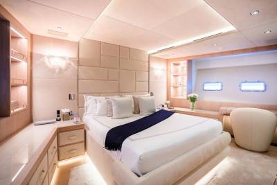 Luxurious yacht stateroom features a plush bed, elegant lighting, and porthole windows offering a serene escape.