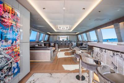 Luxurious yacht interiors feature vibrant artwork, plush seating, and panoramic windows overlooking the ocean.