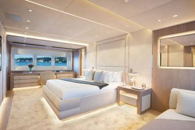 Luxurious yacht stateroom features a plush bed, elegant cabinetry, and panoramic windows overlooking a serene waterfront.
