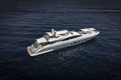 A luxurious white yacht glides across the deep blue ocean under a clear sky.