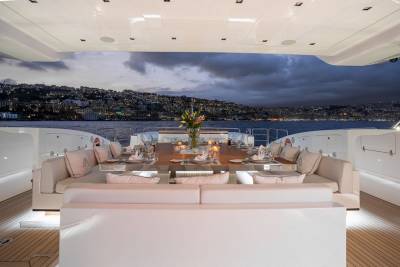 Dine al fresco on a luxury yacht overlooking a glittering cityscape at dusk.