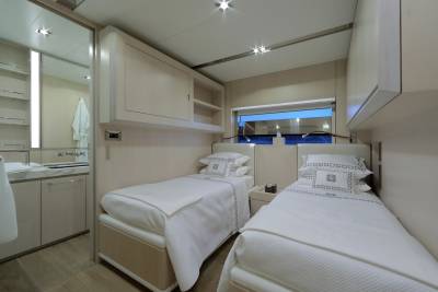 Two twin beds with crisp white linens and decorative pillows are neatly made in this serene cabin.