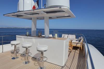 Four white bar stools await guests at the sleek outdoor bar of this luxury yacht.
