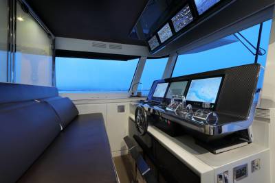 The modern yacht's helm offers a panoramic view of the sea through expansive windows, complemented by advanced navigation displays.
