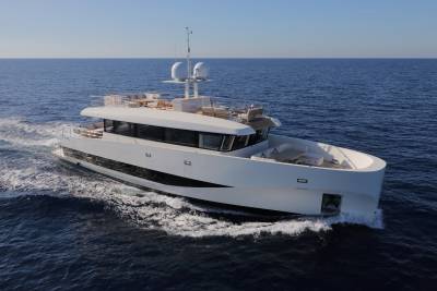 A sleek white superyacht glides through the deep blue ocean on a clear, sunny day.
