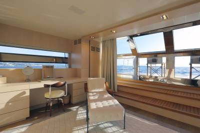 A chaise lounge and vanity area offer luxurious relaxation with stunning ocean views from this yacht's interior.