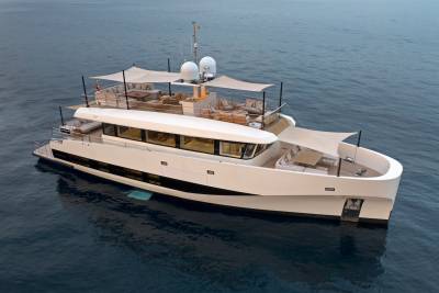 A sleek white yacht with ample deck space for lounging glides across the calm blue ocean.