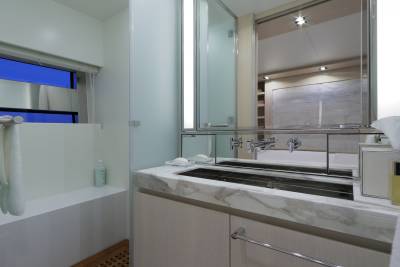 A sleek, modern bathroom features a marble vanity, integrated sink, and a large mirrored cabinet reflecting a luxurious interior.