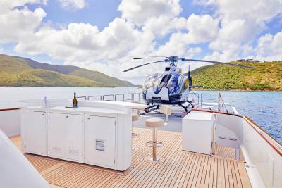 A sleek helicopter rests on the deck of a luxurious yacht, ready for island hopping in a tropical paradise.