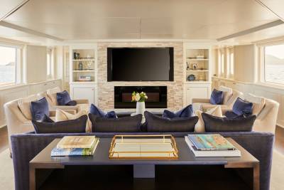 Luxurious yacht salon features plush seating, a modern fireplace, and stunning ocean views through large windows.