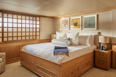 This serene bedroom features a king-sized bed with crisp white linens, a wooden frame with storage drawers, and three framed art pieces above the headboard.