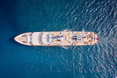 An opulent yacht glides through the deep blue ocean, its helipad and deck furniture hinting at luxurious adventures.