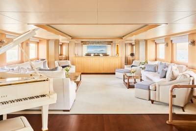 A grand piano and plush seating create a luxurious lounge aboard a yacht with ocean views.