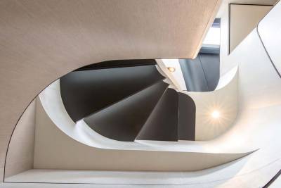 A modern spiral staircase with dark steps and flowing white railings creates a dramatic architectural statement.