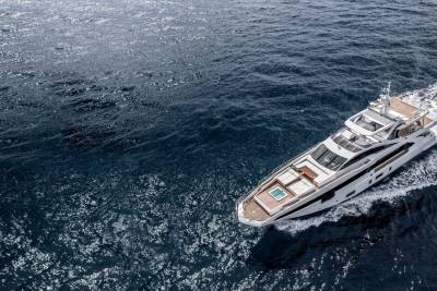 A sleek white yacht glides through the deep blue ocean, leaving a foamy wake behind it.