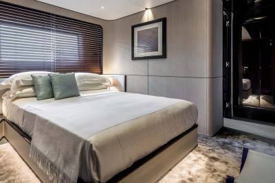 Luxurious yacht cabin features a plush bed, elegant blinds, and a framed seascape artwork.
