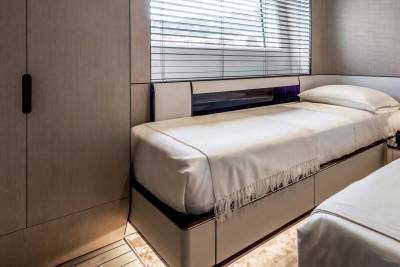 Luxurious twin beds with crisp white linens and a fringed throw are perfectly arranged in this elegant yacht cabin.