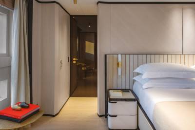 A luxurious bedroom features a comfortable bed, stylish nightstand, and a large window overlooking the ocean.