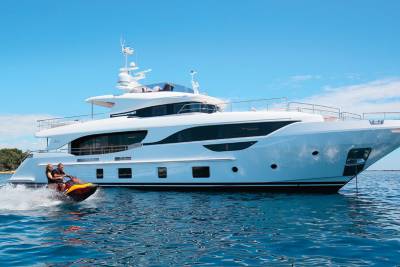 A couple enjoys a thrilling ride on a jet ski in the sparkling blue waters near a luxurious white yacht.