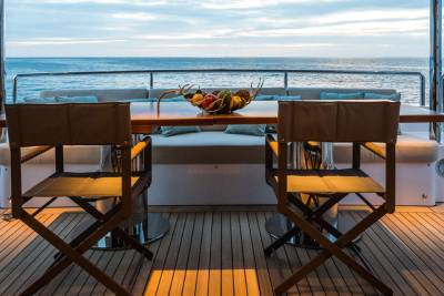 Dine al fresco on the deck of a luxury yacht as the sun sets over the tranquil ocean.