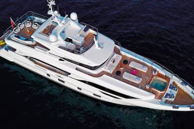 A luxurious white yacht glides through dark blue waters, featuring multiple decks with seating and a hot tub.