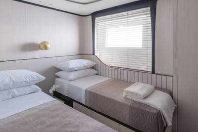 Twin beds with crisp white linens are neatly made in this serene cabin, ready for a restful night's sleep.