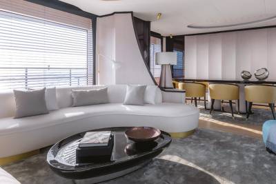 A modern yacht lounge offers a serene escape with its plush white sofa, sleek coffee table, and elegant dining area.