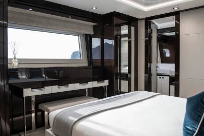 Luxurious yacht interior features a spacious bedroom with a vanity and a large window offering scenic views.