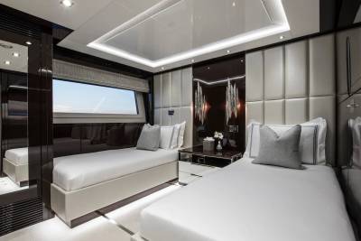 Luxurious twin beds with crisp white linens and plush pillows await in this elegant yacht stateroom.