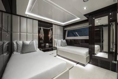 Luxurious twin beds with plush headboards and modern lighting create a serene retreat aboard this elegant yacht.