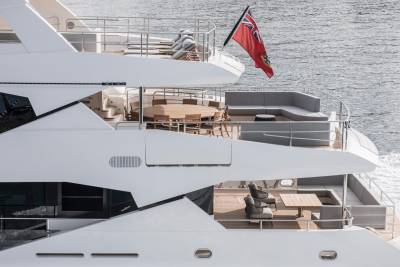 A luxurious yacht glides through the water, its decks adorned with elegant seating and a large dining table.