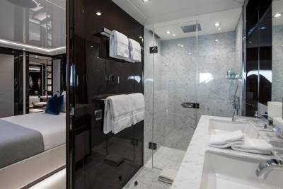 Luxurious marble bathroom with a glass-enclosed shower and dual sinks complements the adjacent opulent bedroom.