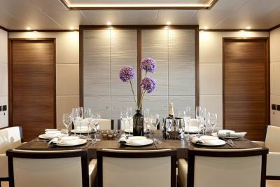 A beautifully set dining table awaits guests aboard a luxurious yacht, complete with fine china, crystal glasses, and a chilled bottle of champagne.