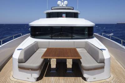 A modern yacht with plush seating and a wooden table offers a luxurious spot for al fresco dining on the open sea.